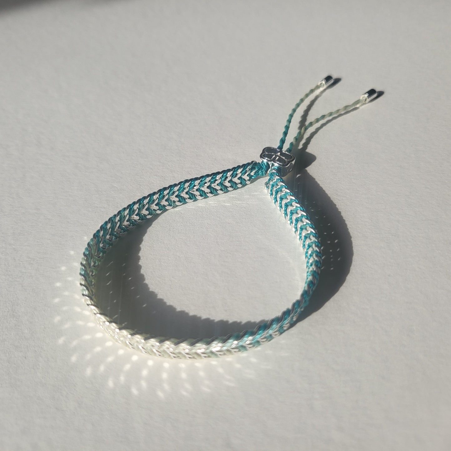 Braided bracelet with silver, blue and green pattern