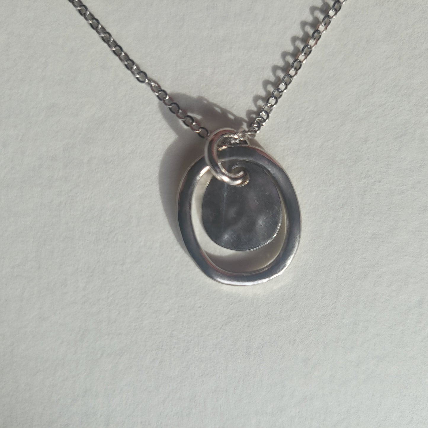 Silver necklace with a pendant on a light gray background