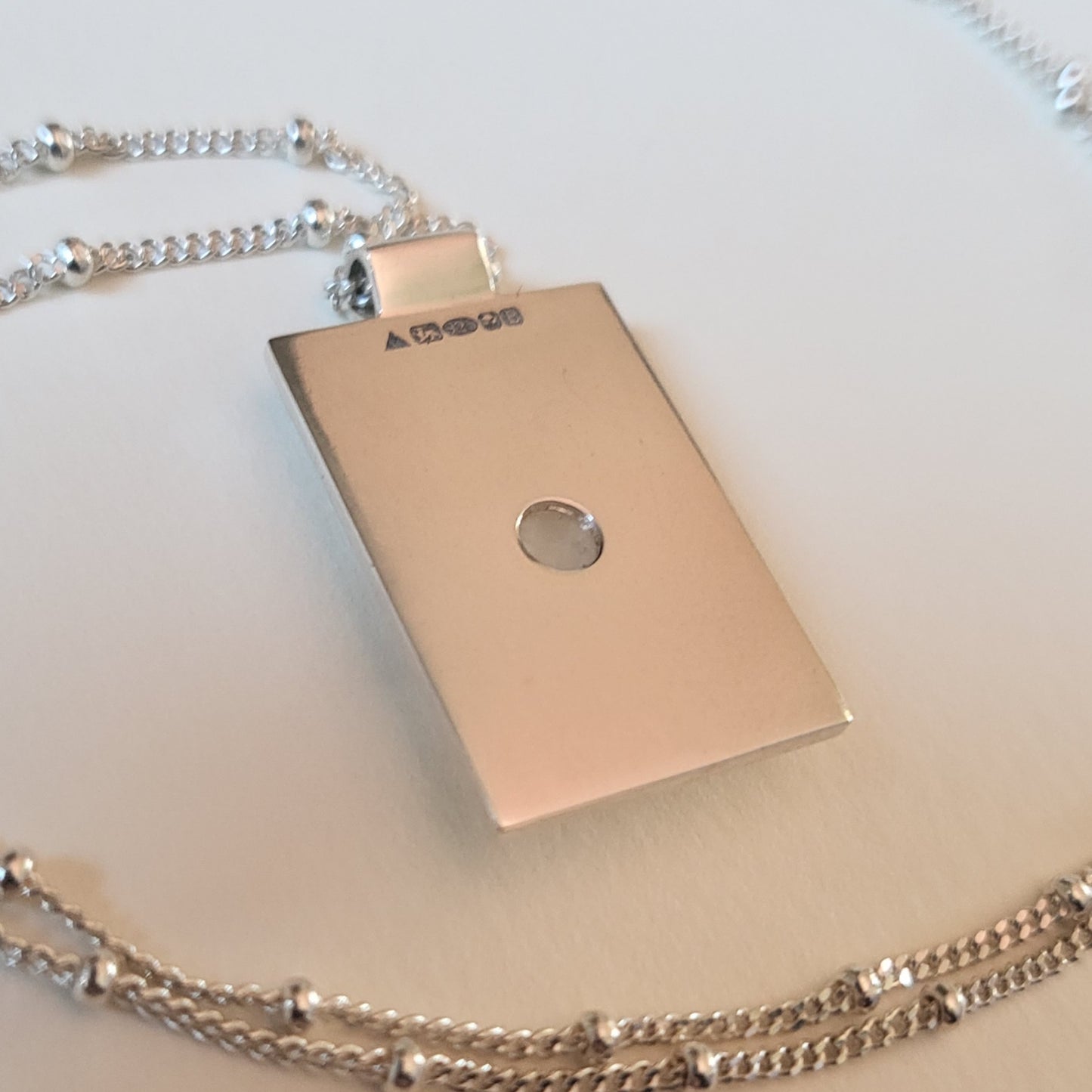 Silver pendant with chain on a light background