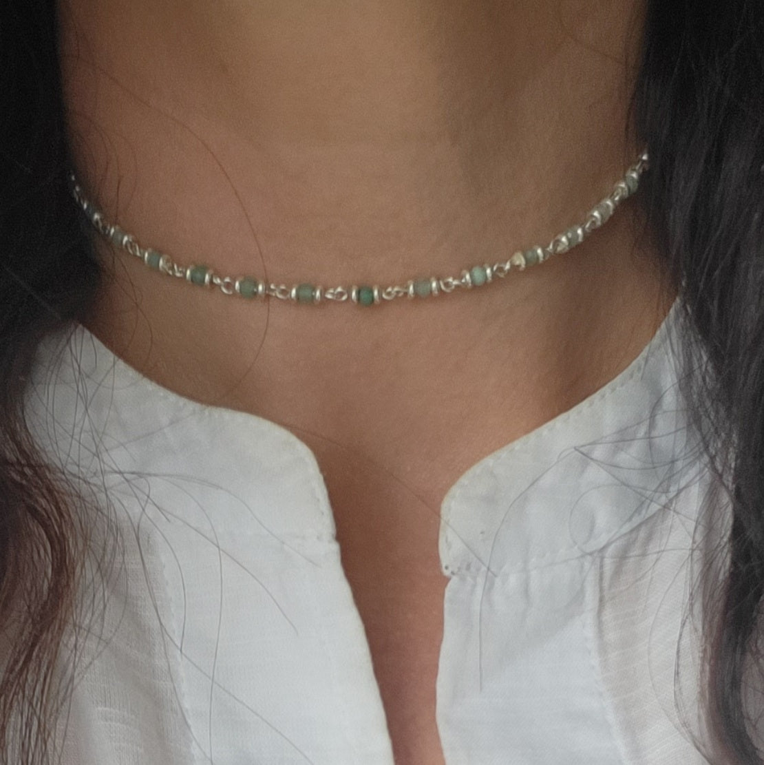 Close-up of a person wearing a delicate choker style Amazonite and silver necklace.