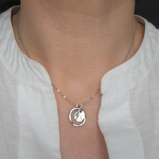 Adjustable silver necklace with hammered pendant worn by person in a white shirt