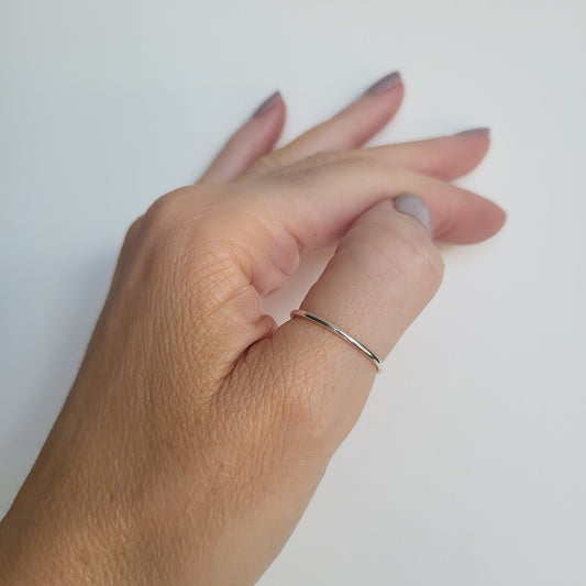 Hand wearing a fine silver ring on a white background