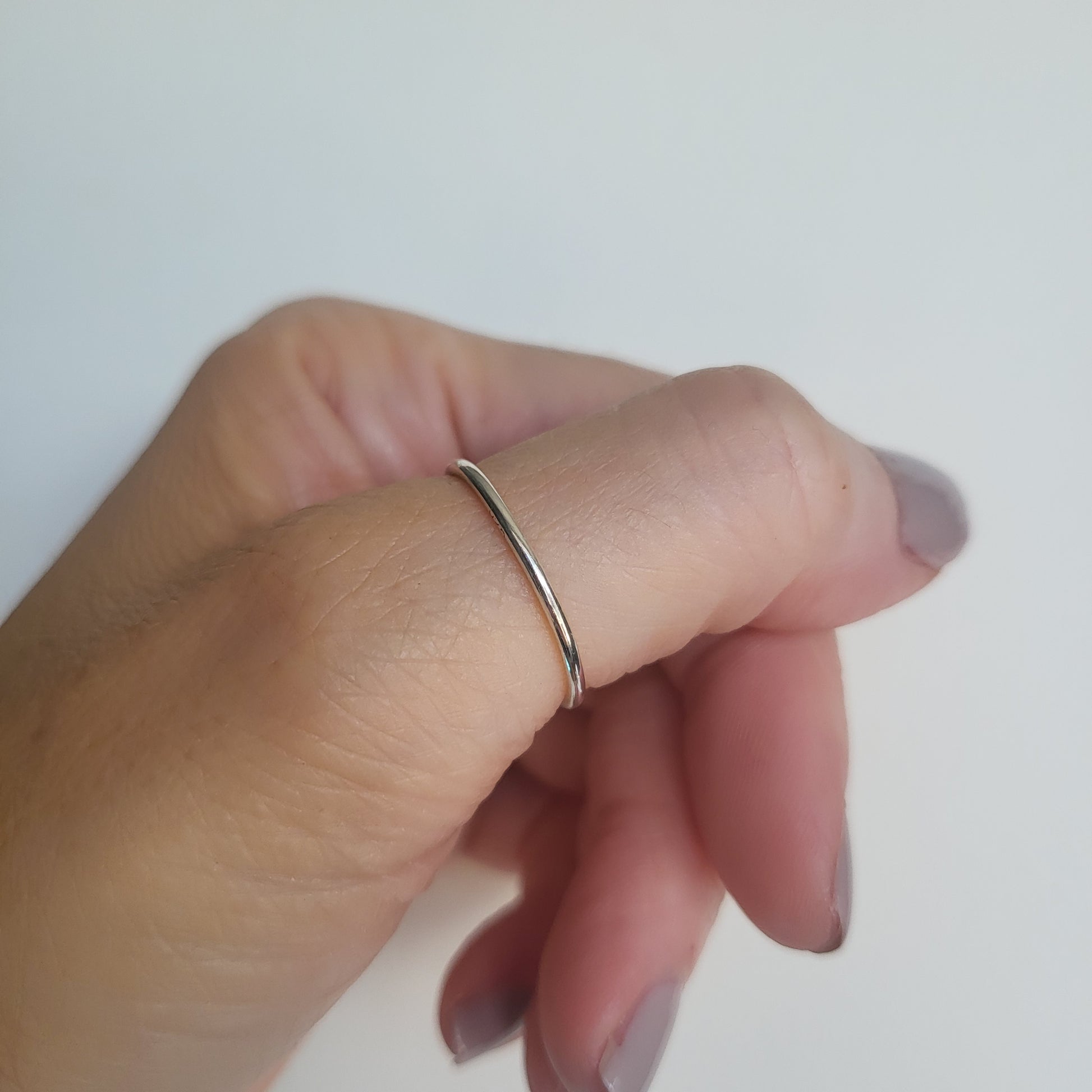 Hand wearing a silver ring on a white background