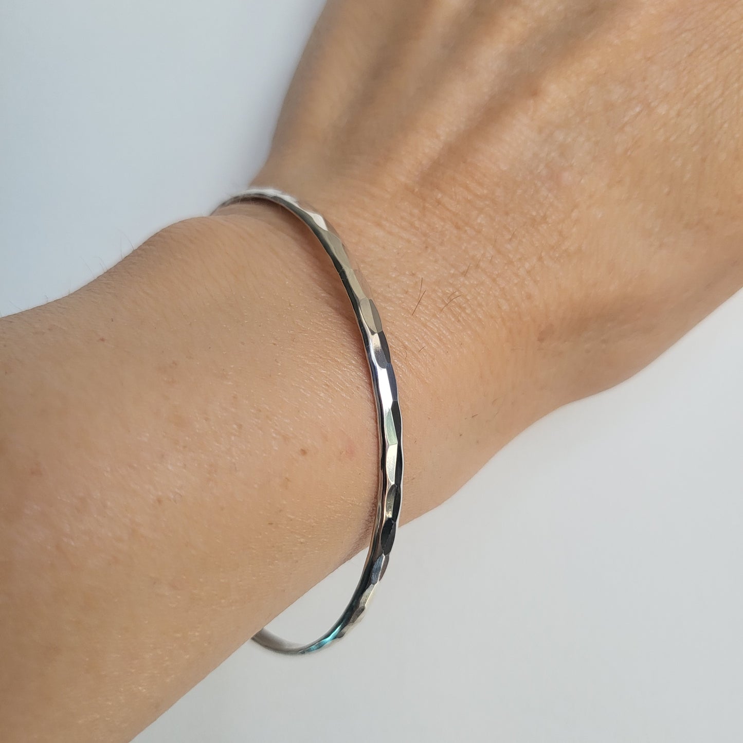 Silver bracelet on a wrist against a white background