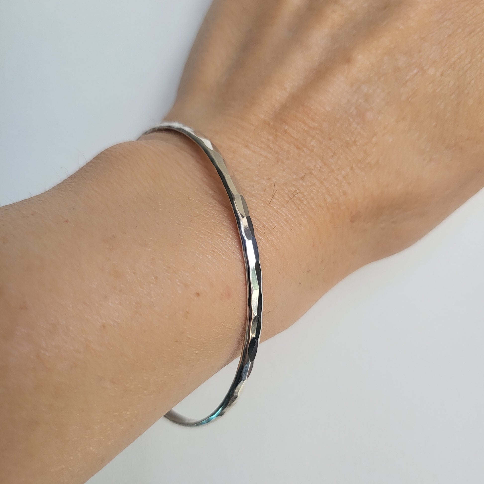 Silver bracelet on a wrist against a white background