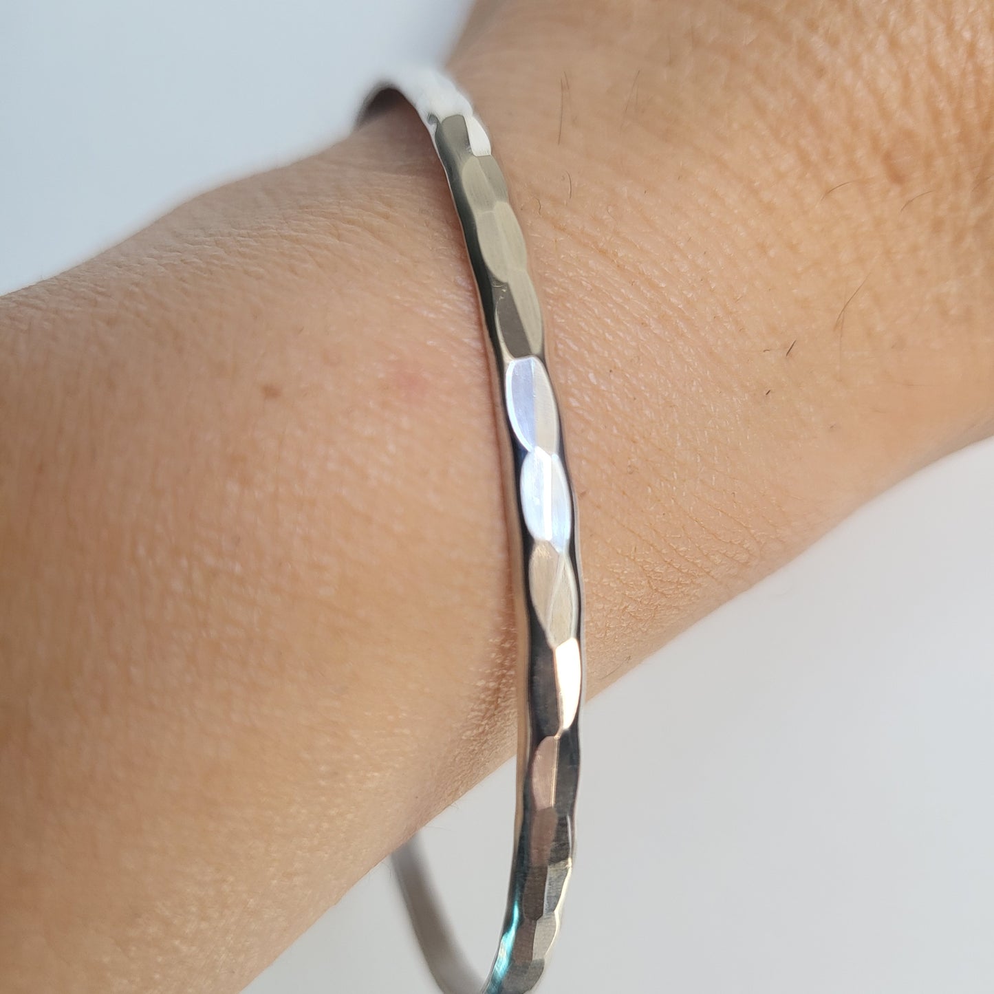 Hammered Silver bracelet on a wrist with a light background