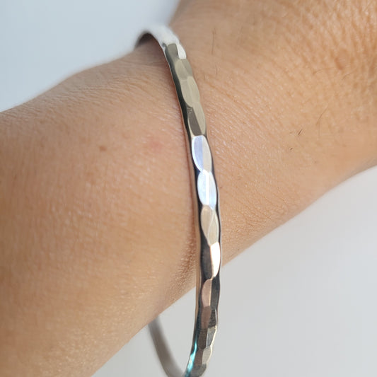 Hammered Silver bracelet on a wrist with a light background