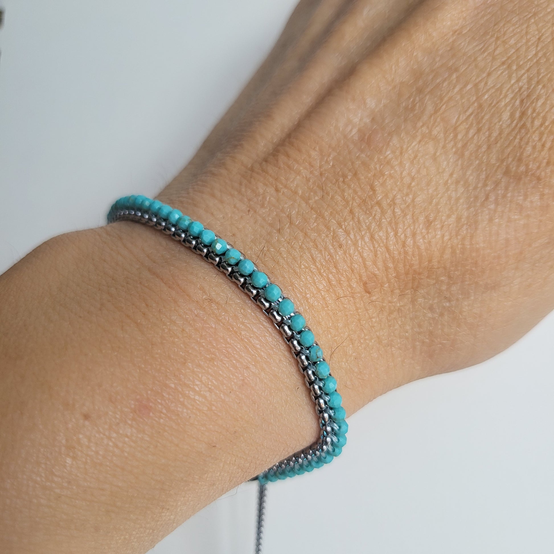 Turquoise beaded bracelet on a wrist against a white background
