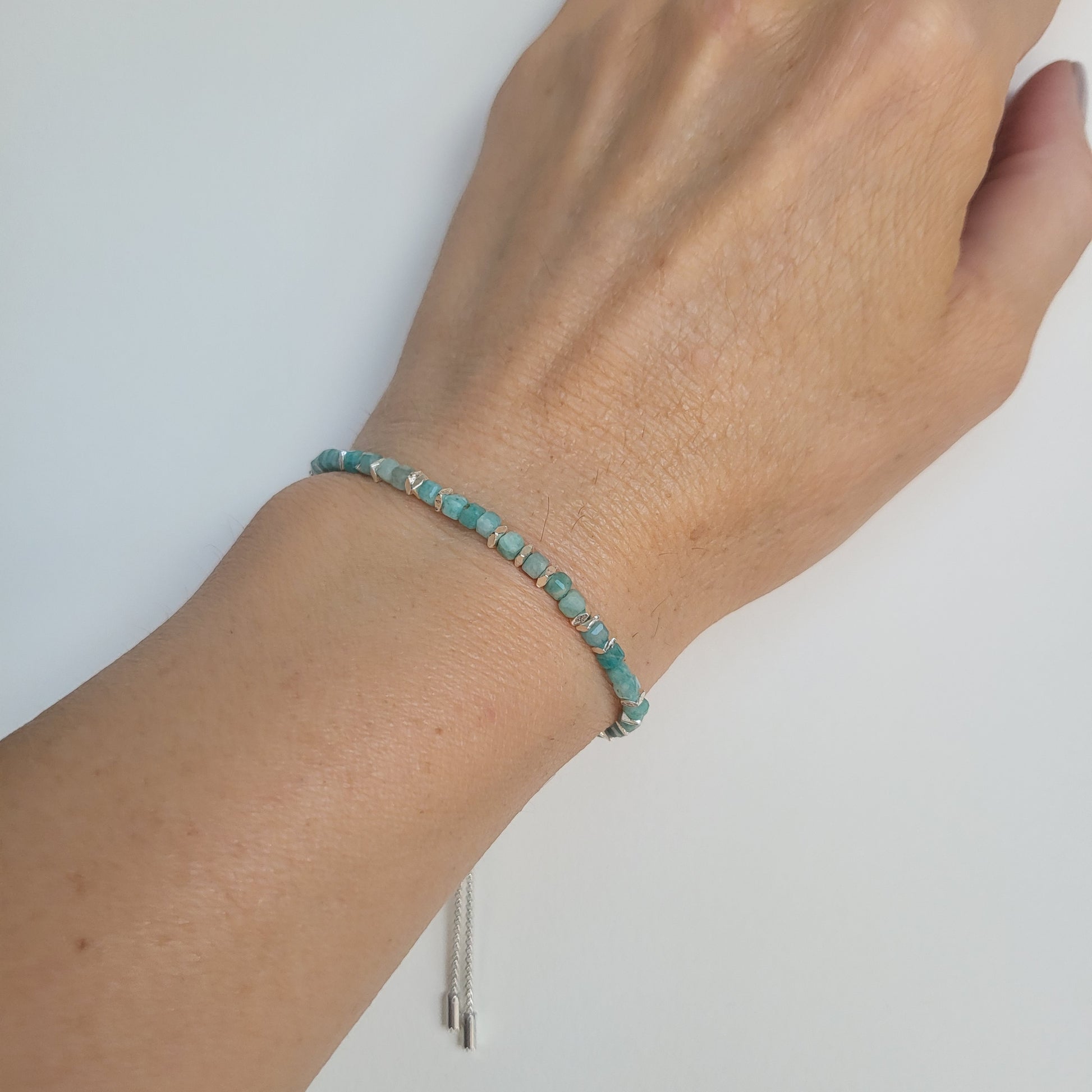 Amazonite and silver beaded bracelet on a wrist against a white background
