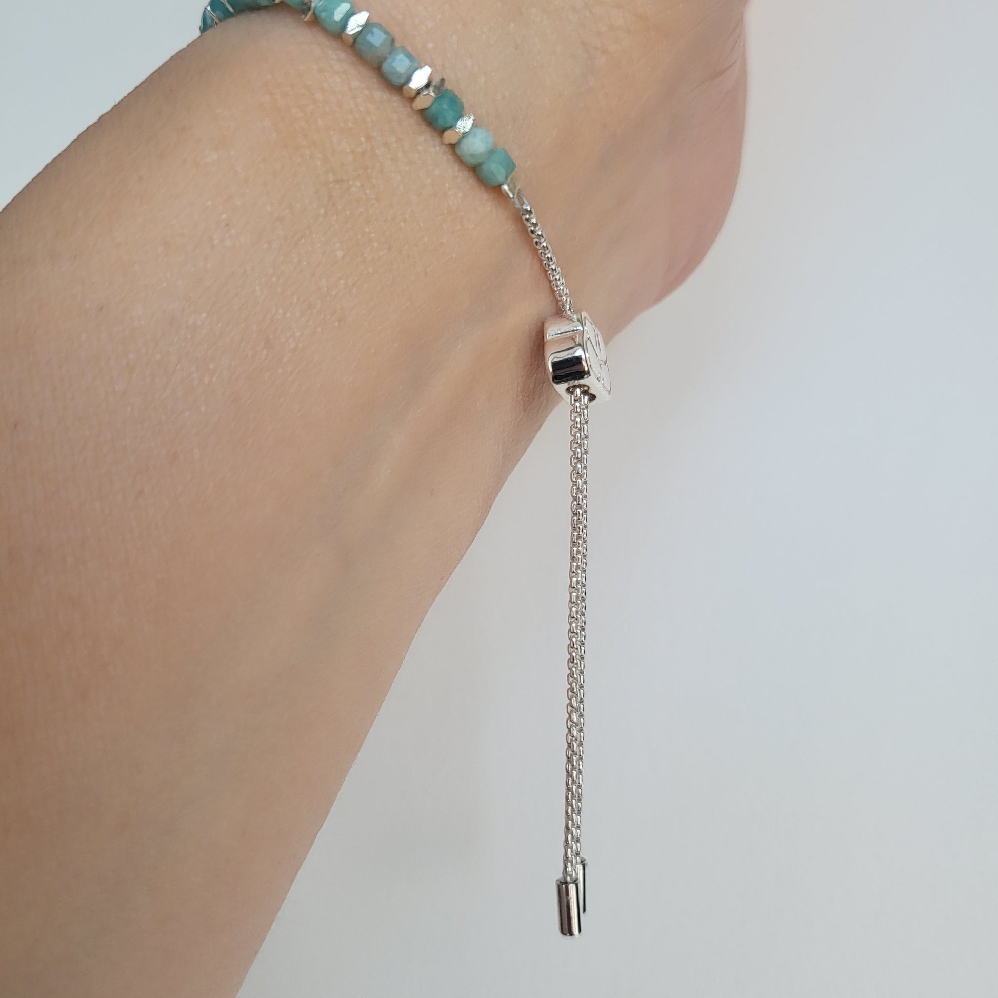 Adjustable, Amazonite beaded bracelet on a person's wrist against a light background