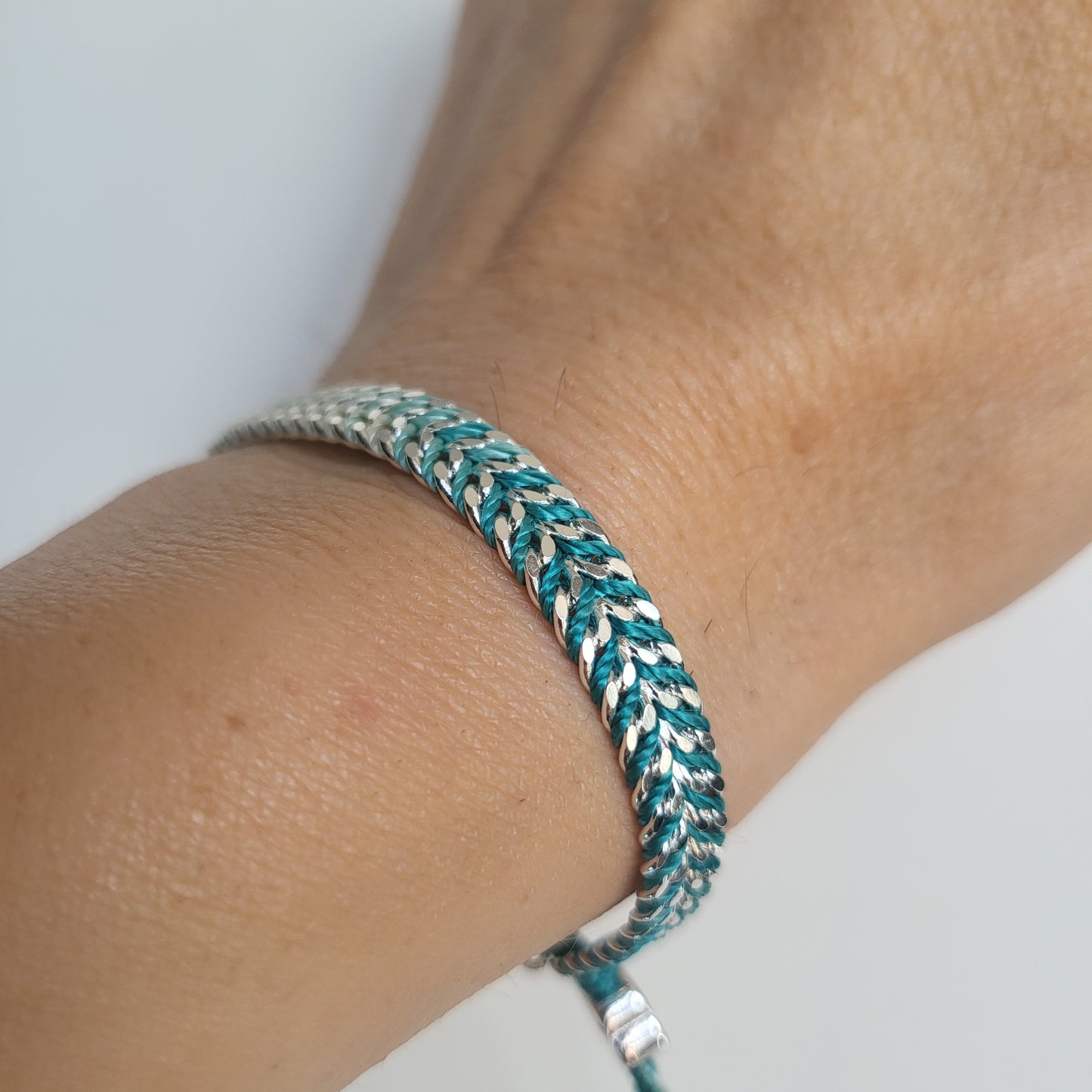 Close-up of a braided bracelet on a wrist with a neutral background