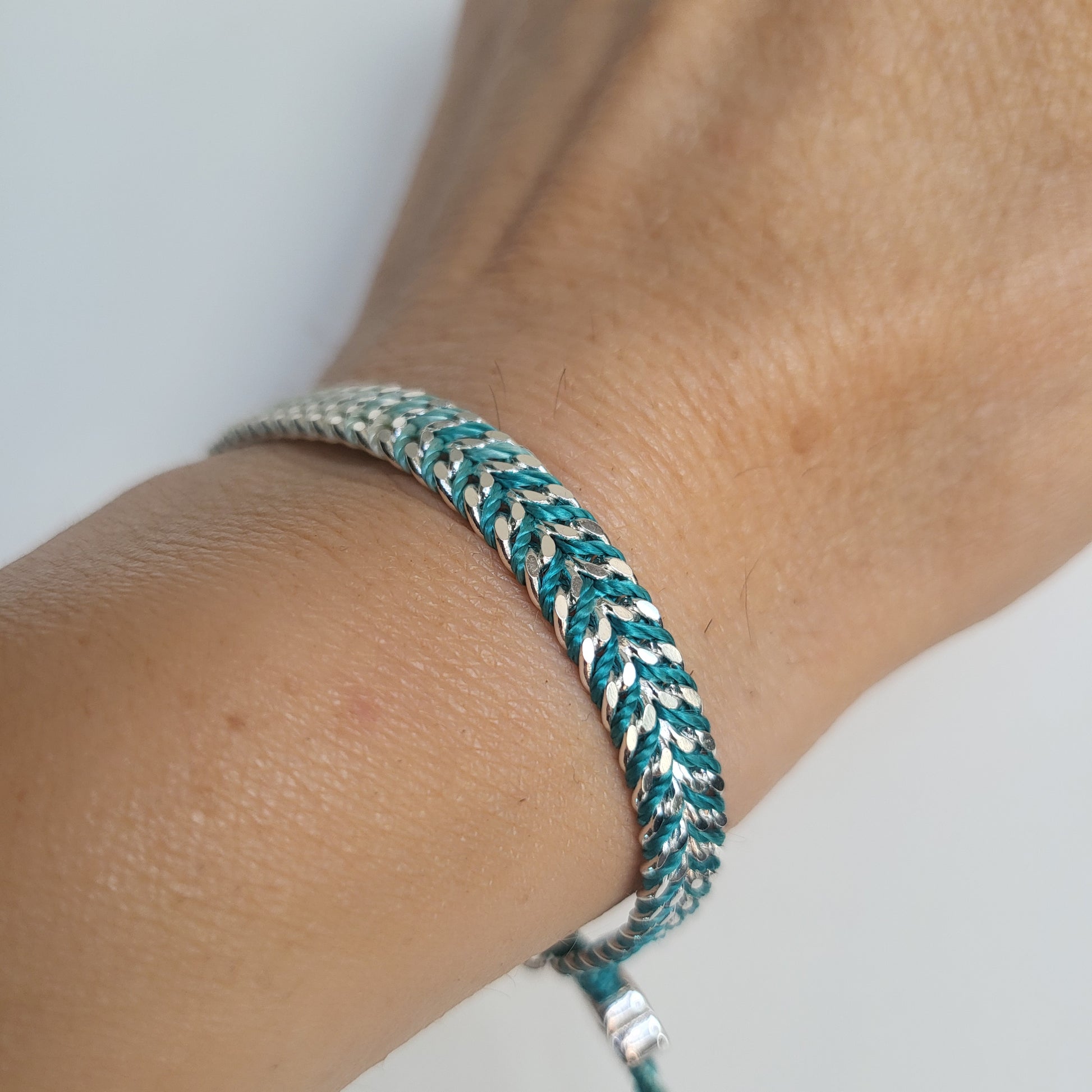 Close-up of a braided bracelet on a wrist with a neutral background