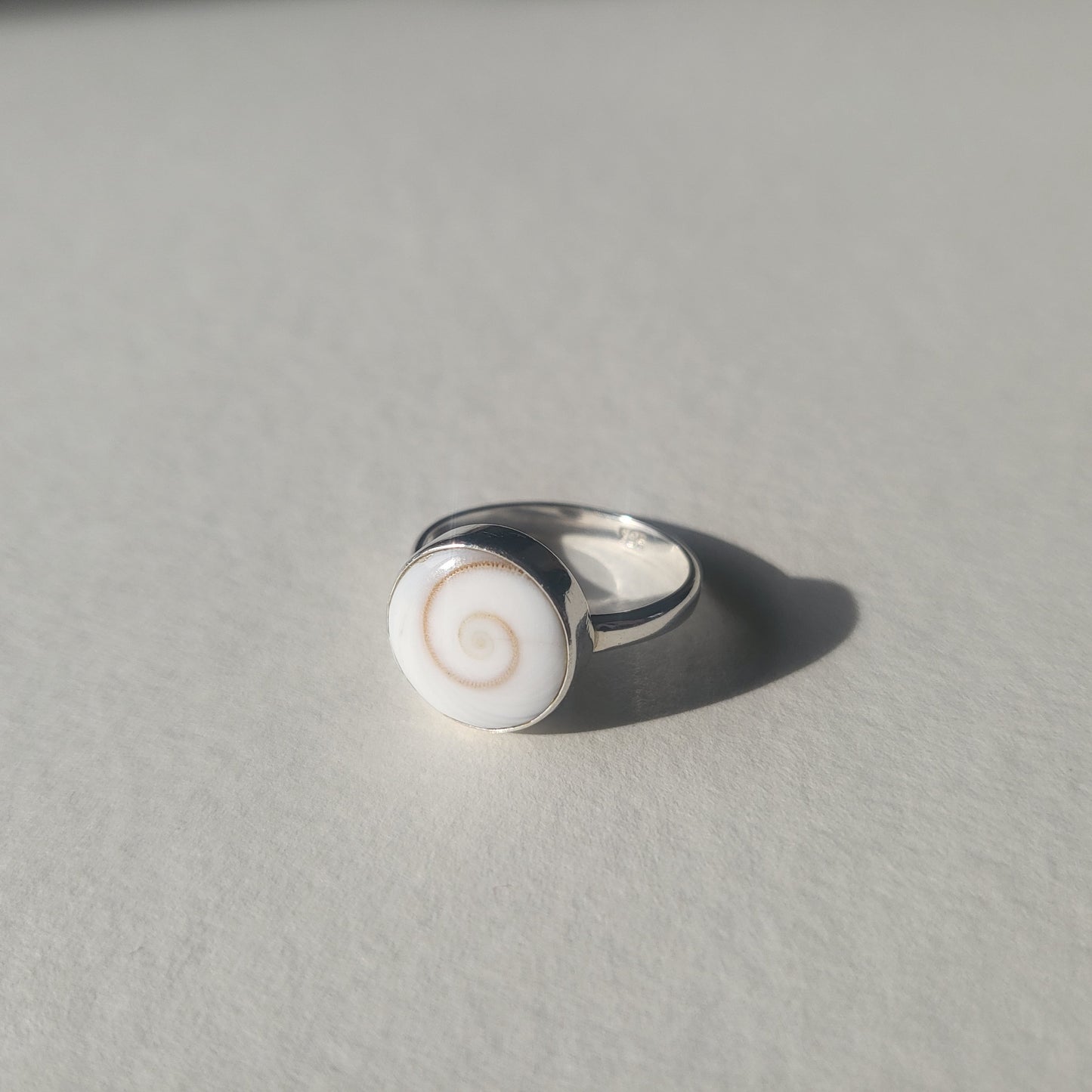 Silver ring with a white circular shell design 