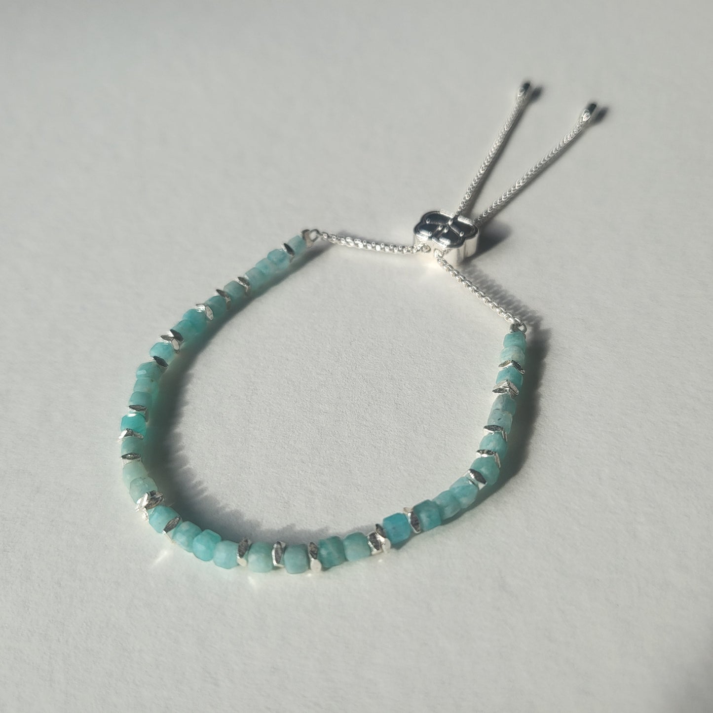 Amazonite beaded bracelet with silver accents on a light grey background