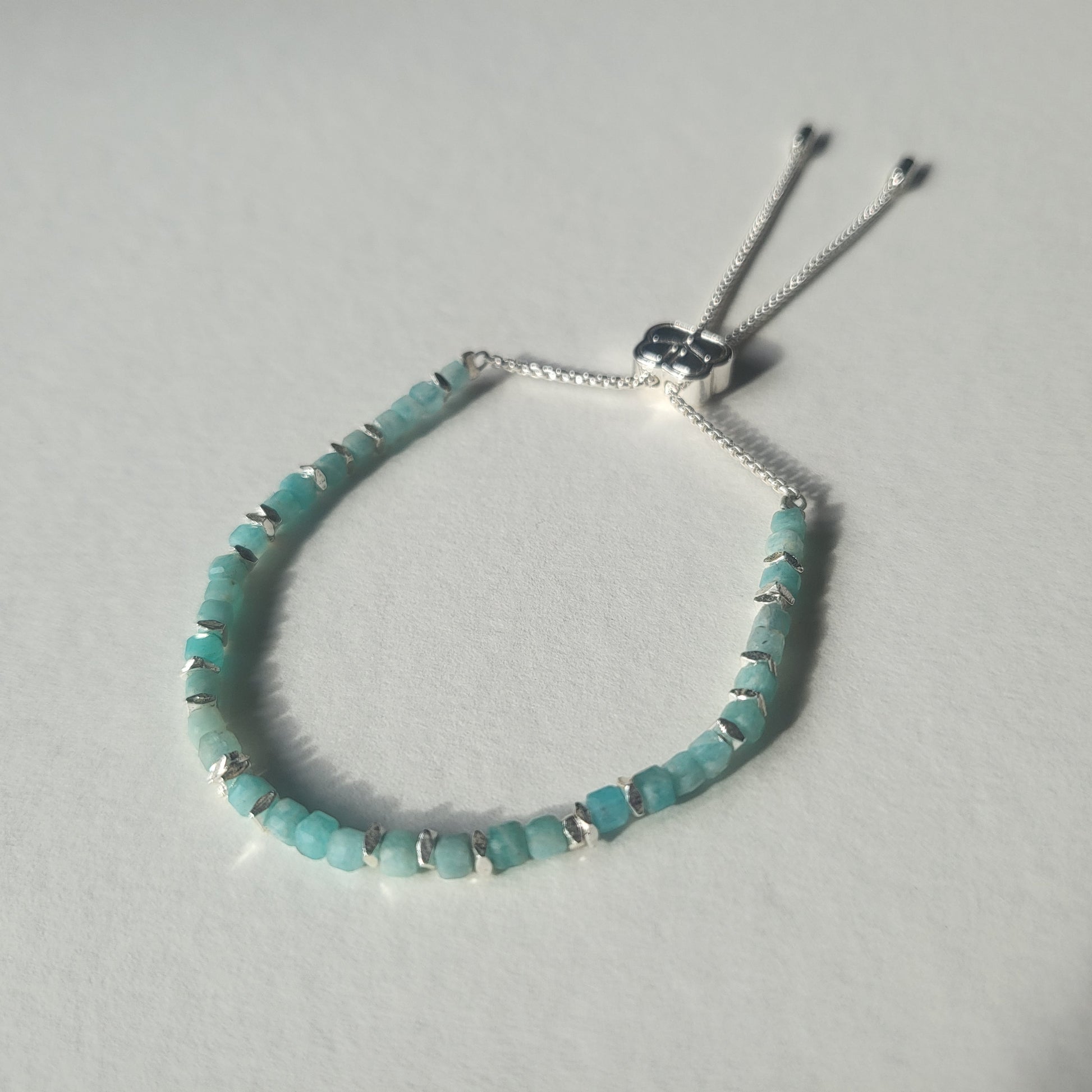 Amazonite beaded bracelet with silver accents on a light grey background