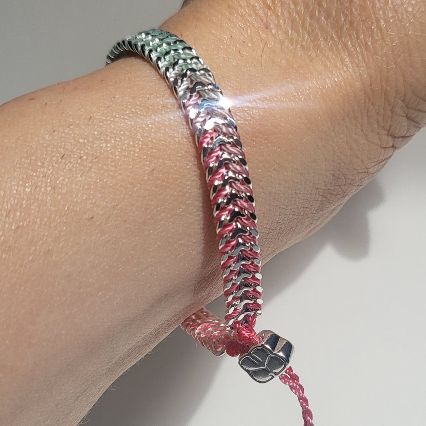Bracelet with pink and black pattern on wrist against a neutral background