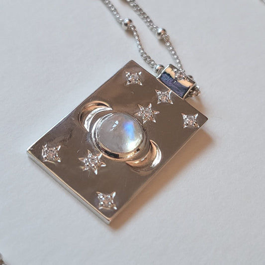 Silver pendant with a central gemstone and star designs on a light gray background