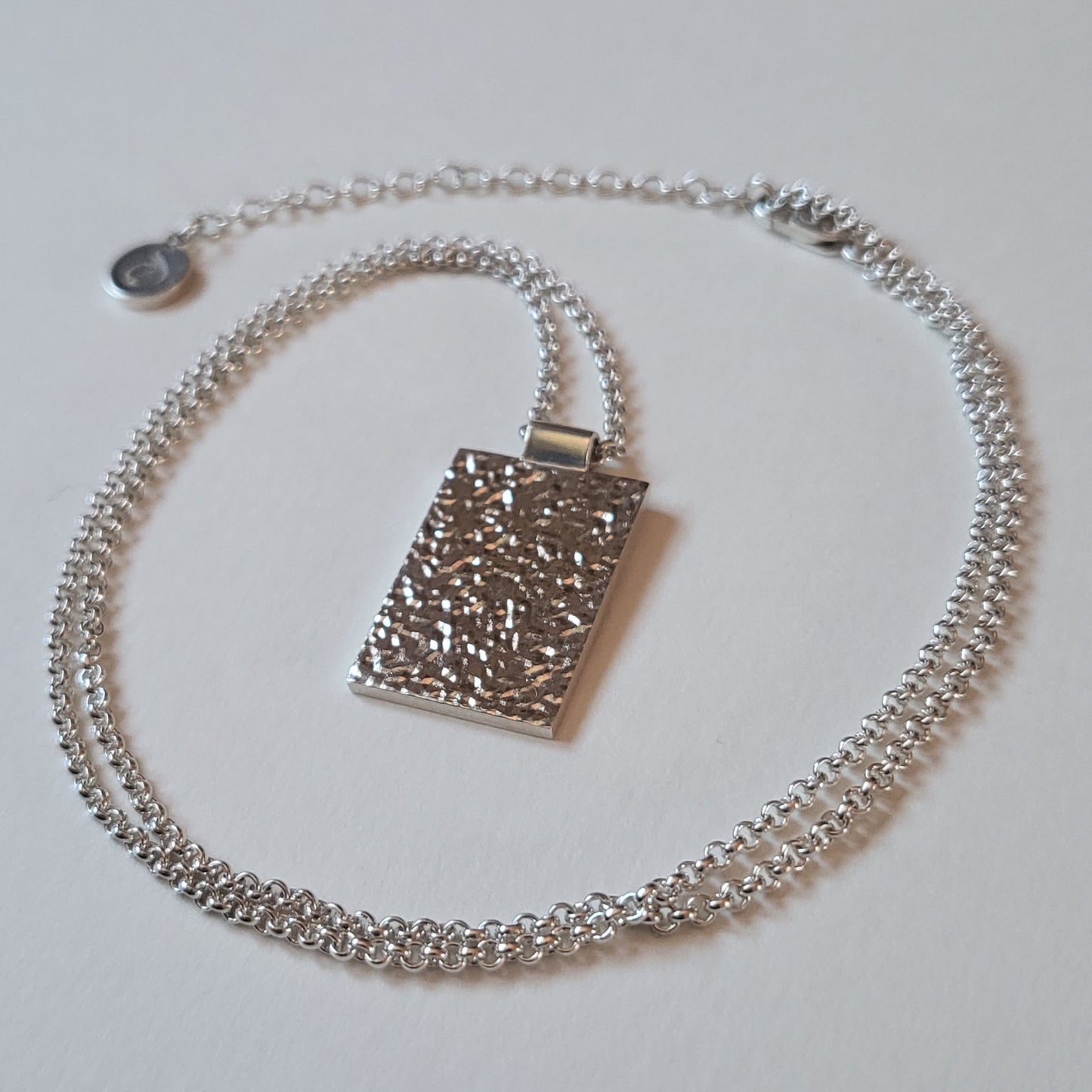 Silver necklace with a pendant on a light gray background