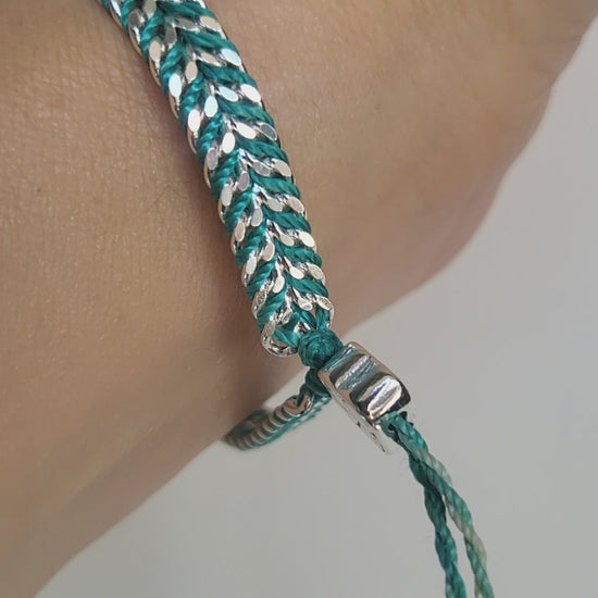 Video of a silver and turquoise braided adjustable bracelet on a wrist against a white background